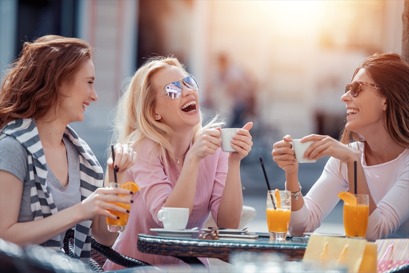 Three women without children meeting at outdoor cafe and enjoying together.